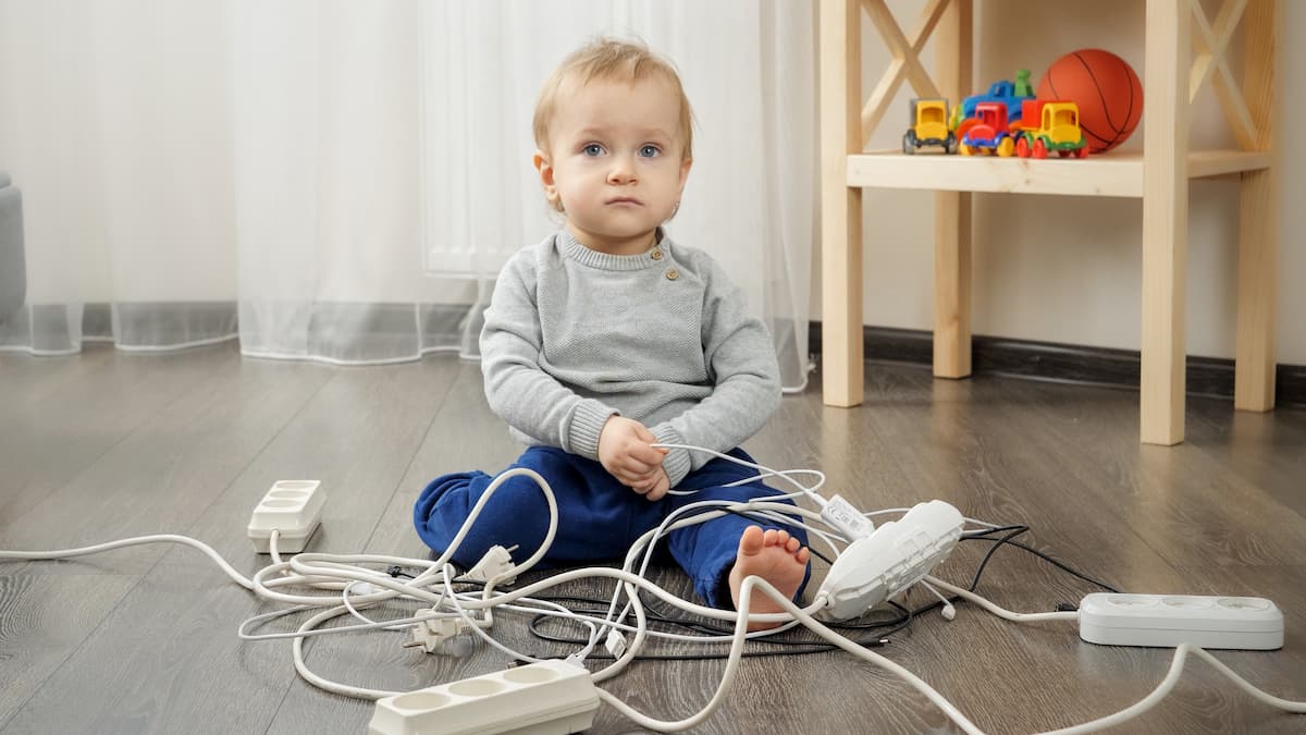 niño jugando con enchufes y cables electricos